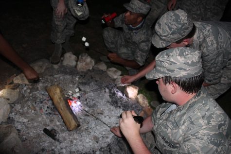 Cadets stick marshmallows into the dwindling bonfire.