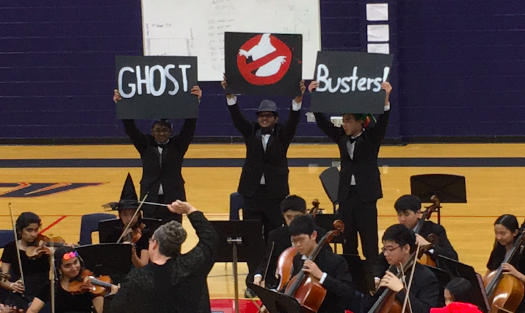 Orchestra students hold up signs to encourage the audience to sing along.