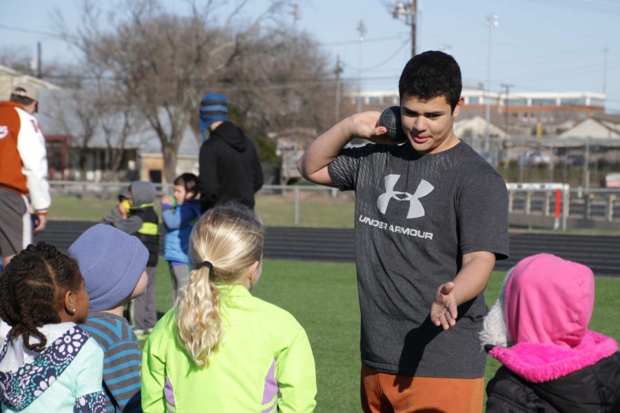 Cesar Estrada 20 teaches the kids how to properly throw the ball for shot put.  
