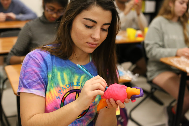 Sofia Penny 18 uses a pen to make marks in her Play-Doh brain. 