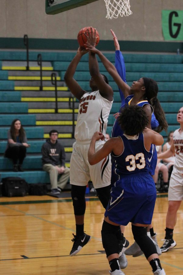 Soaring past her defenders, Kandyce Shepard 17 tries for a basket.