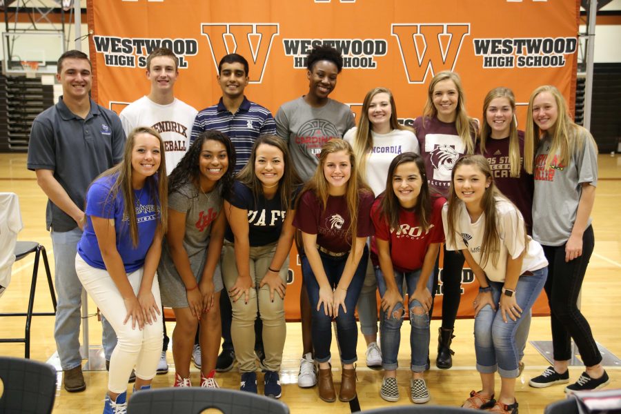 Eighteen athletes pose after signing to their colleges. 