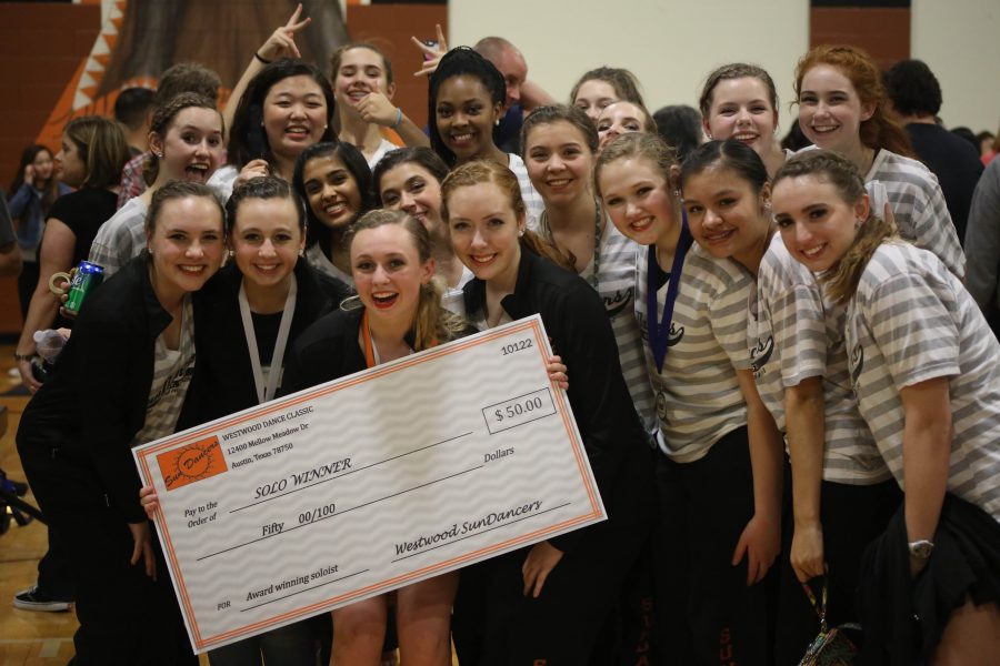 Tory Loper 17 poses with team members while holding her first place check.
