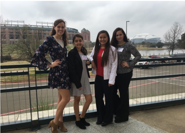 Sam Pearcy, Bethany Gaona, Jena Hawks, Caitlin Dickey stand with the Texas Rangers stadium on the left and the Dallas Cowboys stadium on the right.

