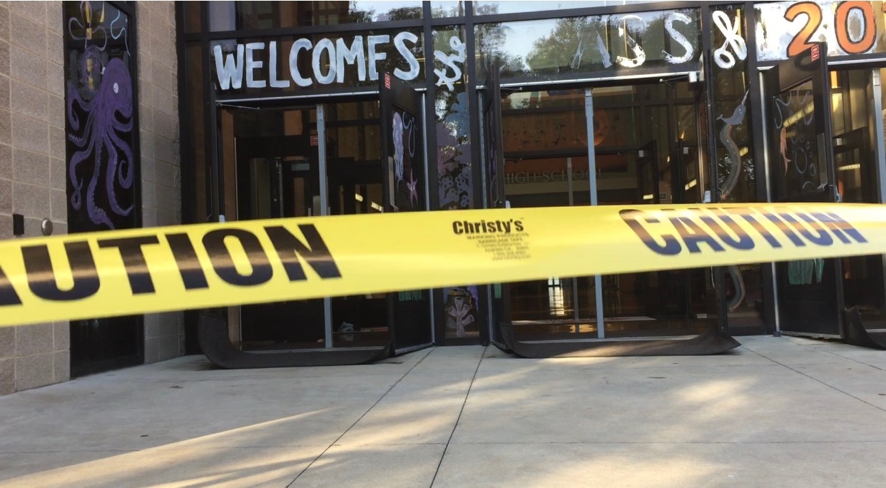Caution tape blocks students from entering through the main entrance.