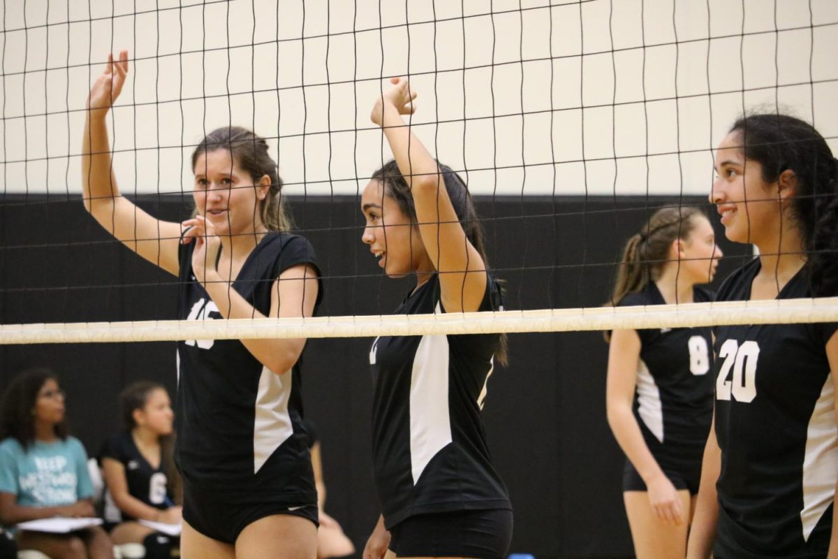 Freshmen Kristen Koporc, Grace Neall, and Isabella Garcia talk amongst each other and prepare themselves at the net.