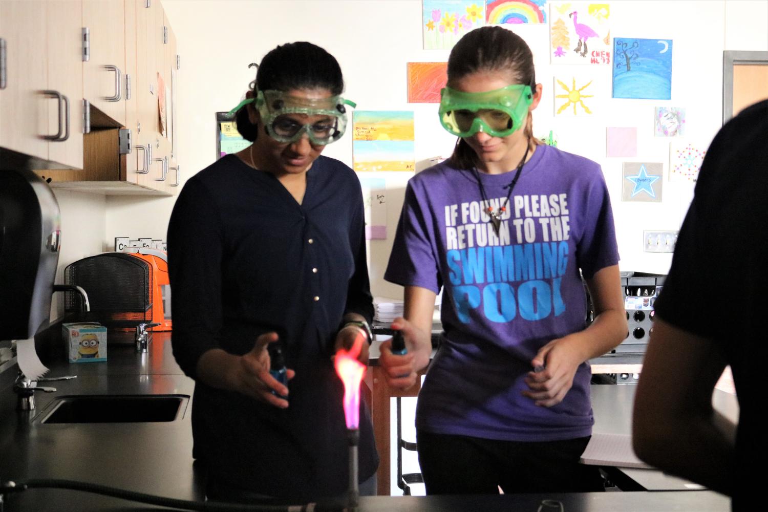 Srishty Pareek 20 and Tracy Hall 20 use spray bottles to create pink fire. 