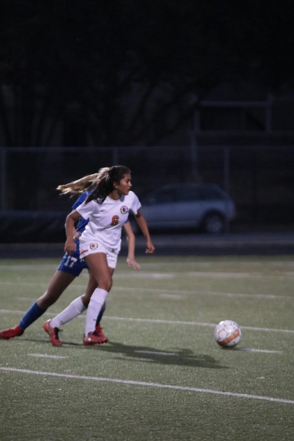 Maya Athreya 20 passes the defender and continues to dribble up the field to the goal.