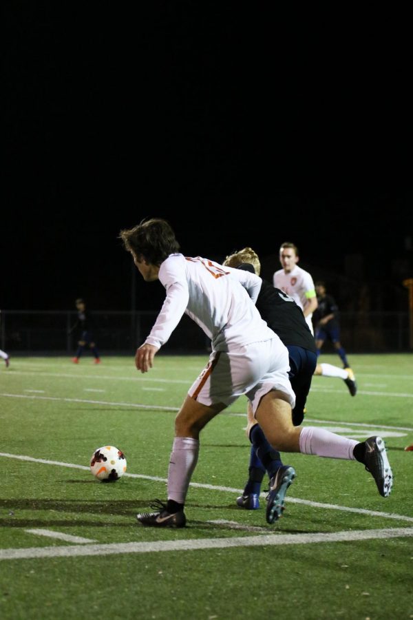 Sam Helwig 19 dribbles the ball away from a Hawk defender. 