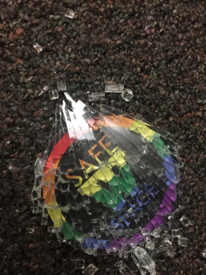 A safe space sticker on the glass panel of the door lies on the ground after being shattered. Photo credit to Ms. Catuogno.