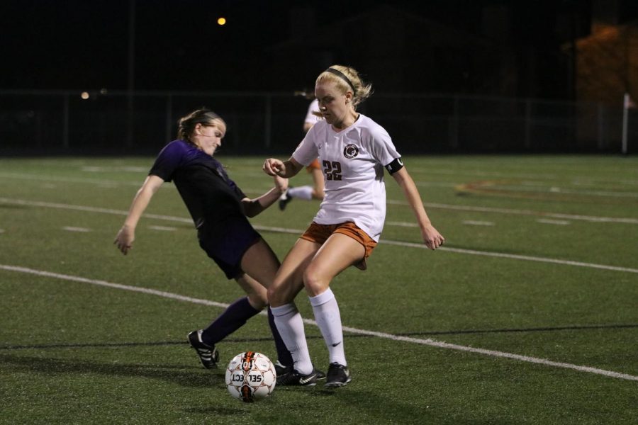 Caroline Gillispie 18 defends the ball from a Raider player.