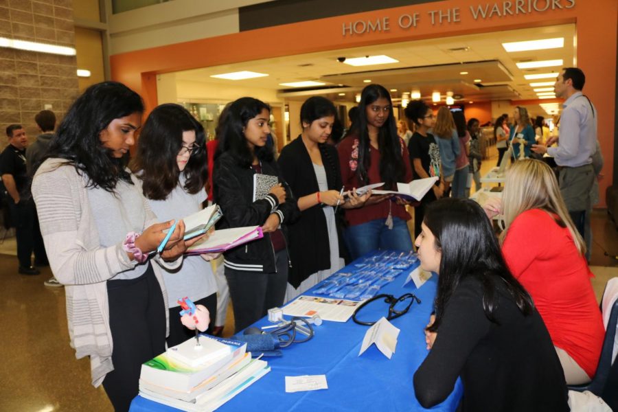 A group of students takes notes at a table at the Health and Science career fair.