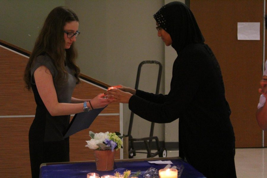 Seyed Mohammed 19 hands a new inductee their candle.