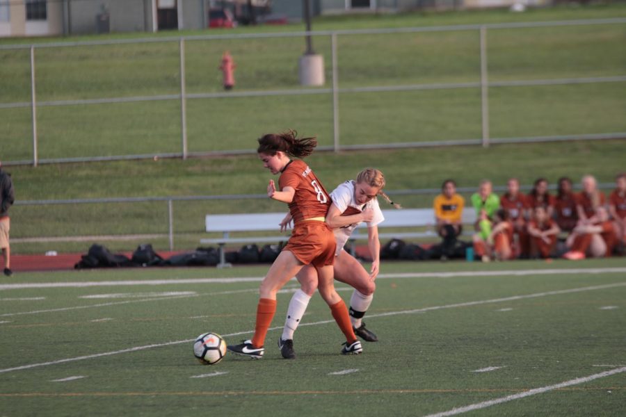 Madison Larrea 19 pushes past Raider as they try to aggressively win back the ball.