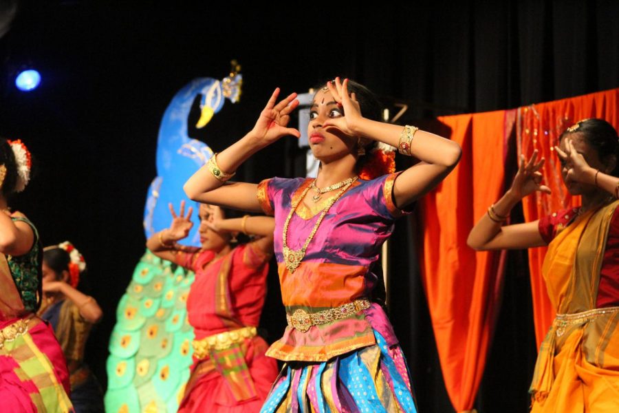 Indian dancers hold their hands up to their faces.