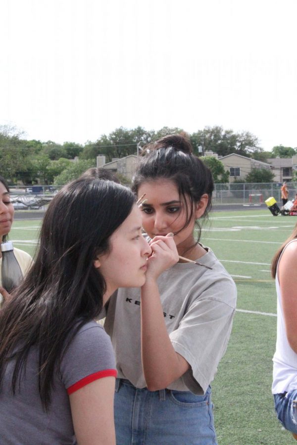 Kate Lee 19 gets a flower painted on her cheek by Alisha Rawal 19.