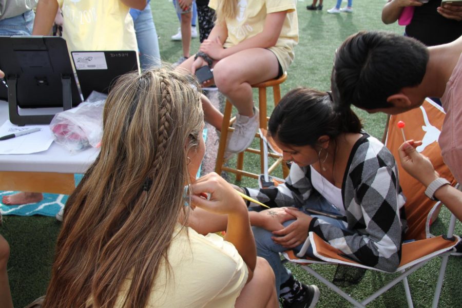 A student receives a henna tattoo at a booth. 