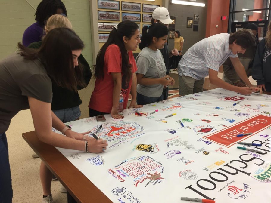 Seniors sign the banner around their future college.