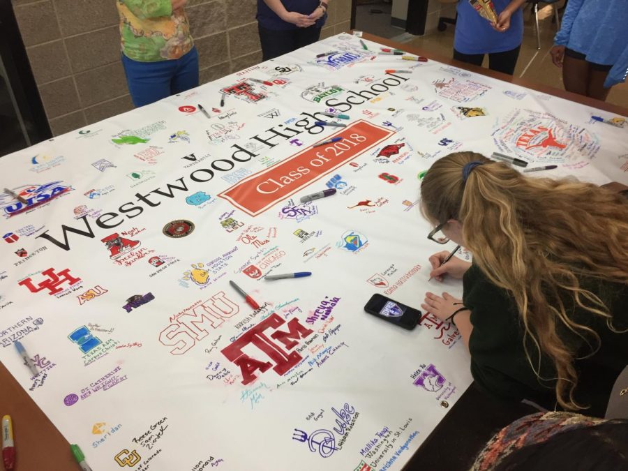 Presley Glotfelty 18 draws a college logo onto the banner.