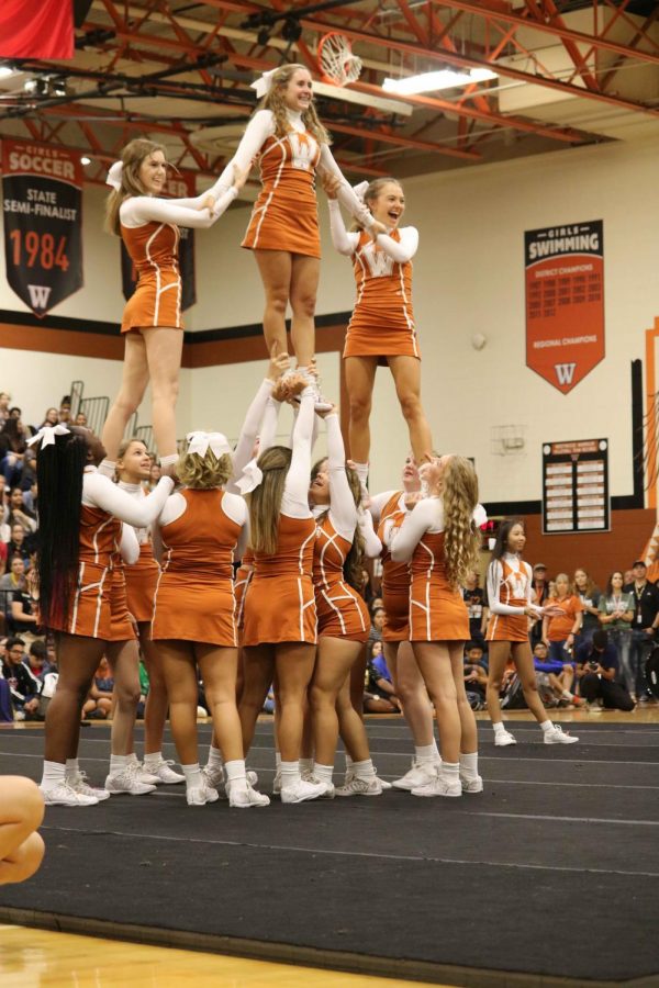 ​Harmony Thornhill 19, Sami Greisdorf 21, and Claire Pitre 21 stand on the top of the pyramid for one of their many cheer stunts.