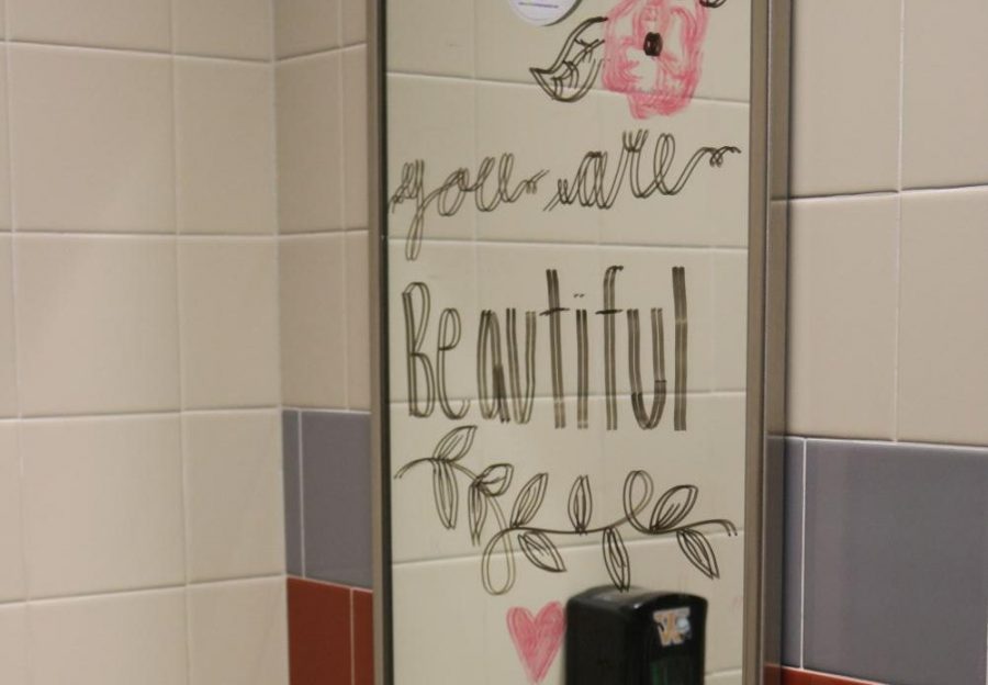 Volunteers decorate bathroom mirrors with positive and encouraging messages, with the hope of increasing school morale.