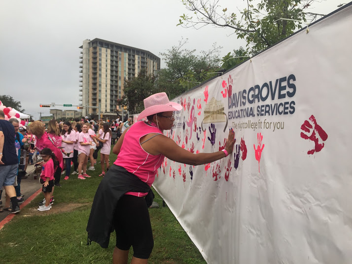 A breast cancer survivor makes her mark by dipping her hands in pink paint and slapping it onto the wall.