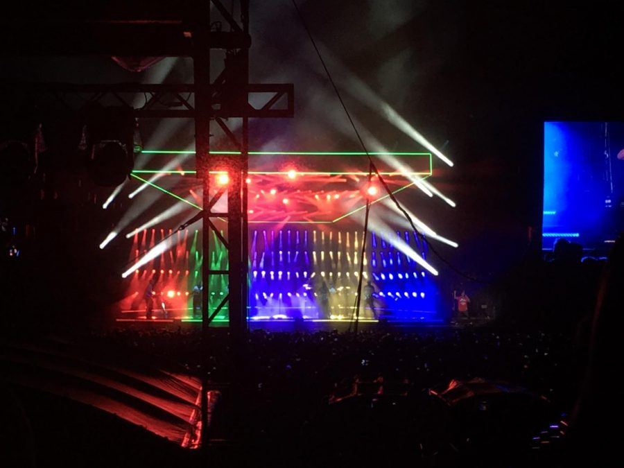 Bruno Mars sings and dances to his opening song Finesse with colorful lights behind him.