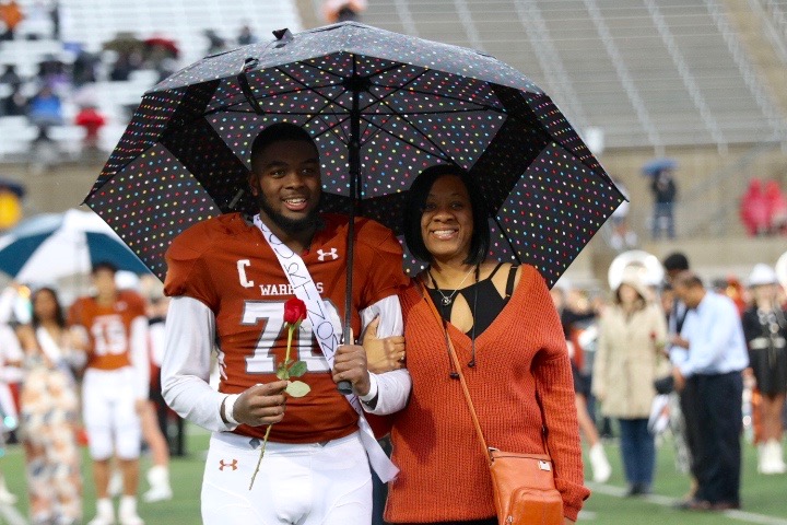 James Jarmon 19 holds a rose while being escorted down the field by his mother.