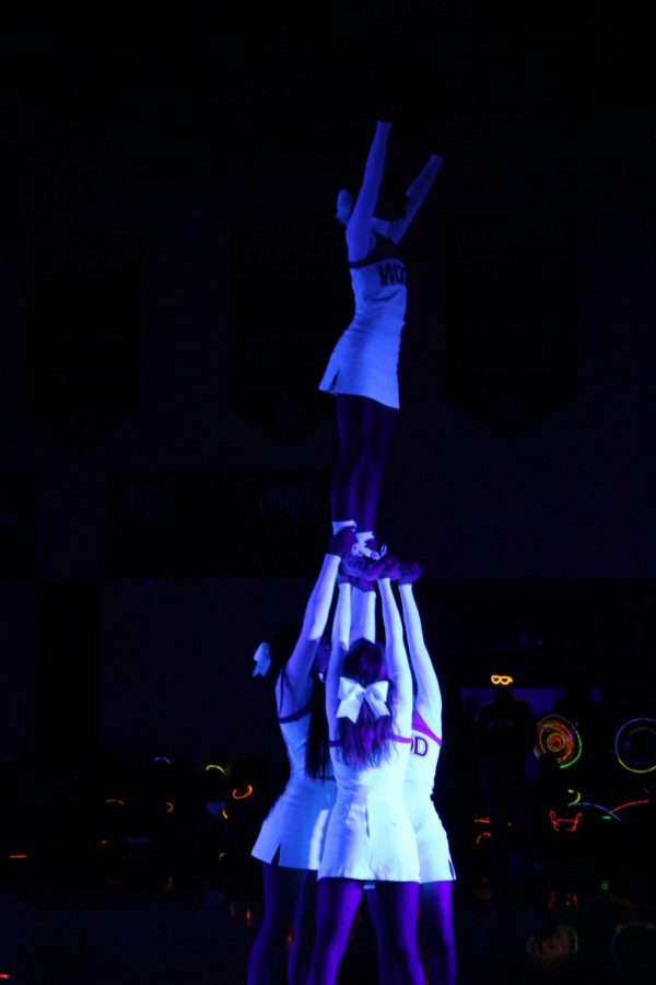 The cheer team does a stunt during their performance.