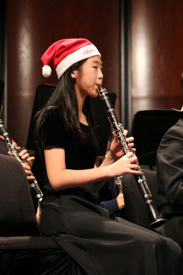 Julia Fang 22 plays the clarinet while wearing a festive holiday hat.