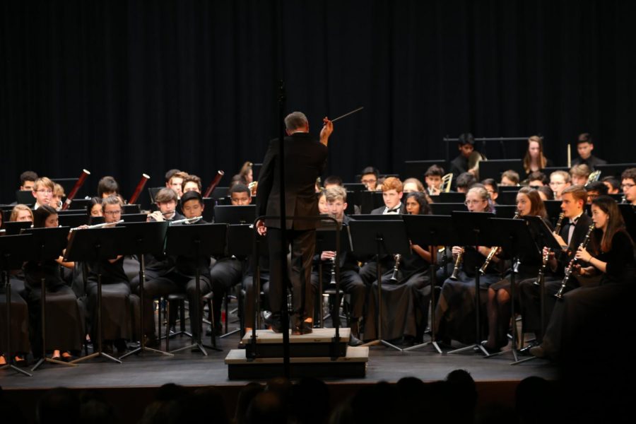The conductor leads the band students during the piece. 