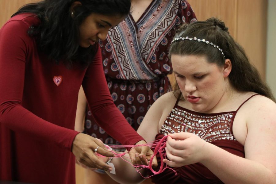 Varshaa Alexis 19 helps her buddy make a pink friendship bracelet.