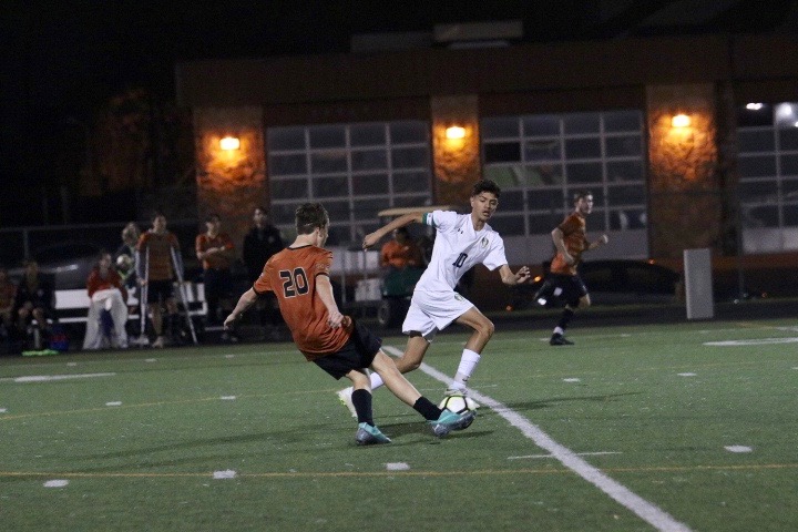 Niko Djordjevic 21 kicks the ball while being guarded by a McNeil player. 