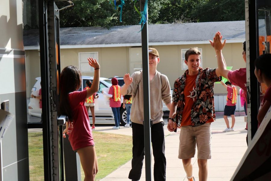 Student volunteers give high-fives to incoming freshmen.