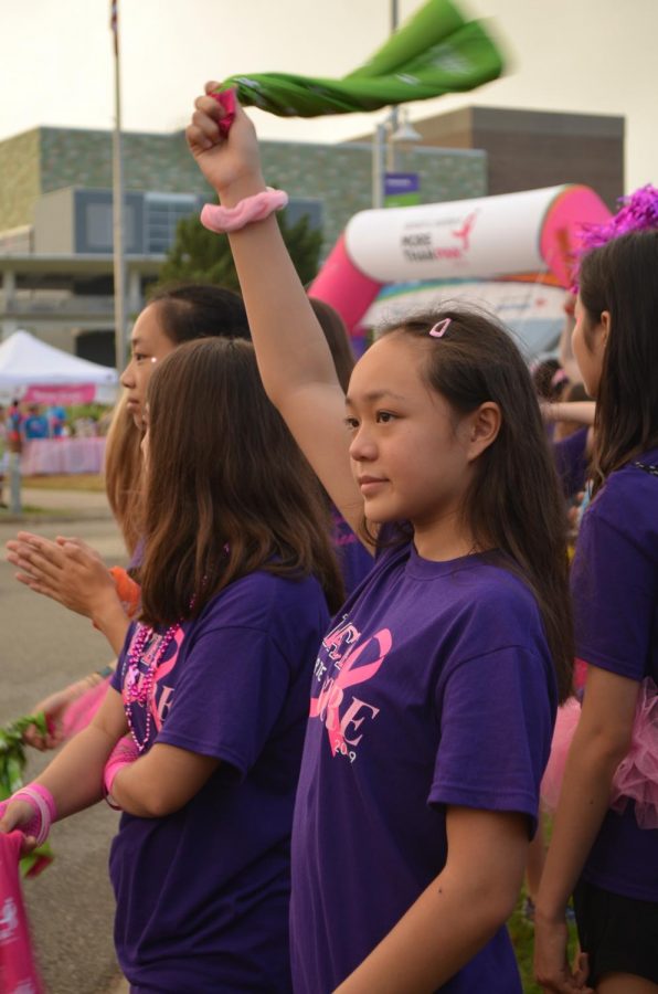 Tiffany Phu 22 raises her Komen wrap as participants walk by. The Komen wrap is a new addition for the More than Pink Walk. 