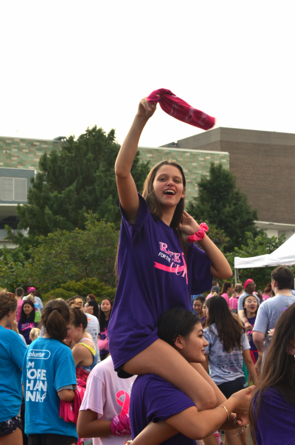 Abby Wignall 22 happily waves the Komen wrap the race provides for all participants. Wignall is part of the cheer organization that is annually invited to encourage the walkers before and after the event. 