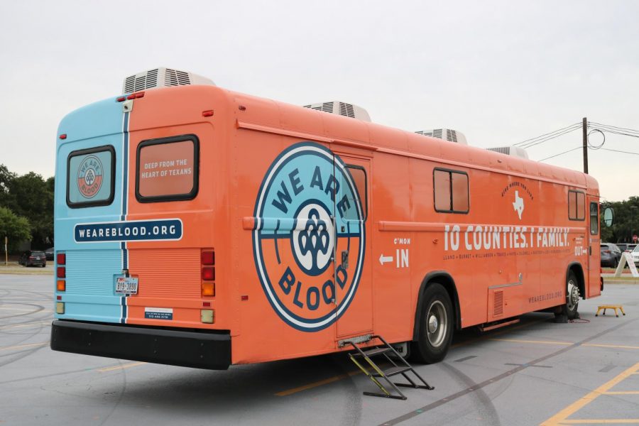 The We Are Blood bus sits in the Westwood Band practice lot with participants donating blood inside.