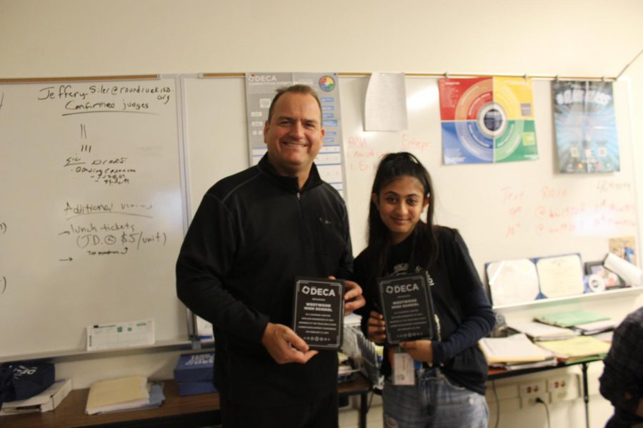 Mr. Jeff Siler and Sakshi Dhavalikar 21 pose with the DECA plaques that were used to show the 8th graders how big our DECA chapter has grown and how well its done.  Ambassadors encouraged them to join career-related clubs to help them gain more knowledge and soft skills.