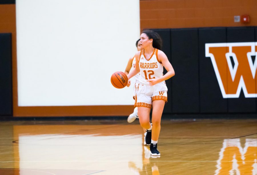 Dribbling down the court, power forward Desi Davalos '22 scans for teammates to make a pass to. Despite efforts from the team, the Lady Warriors were unable to pull ahead of the Raiders during the first half.