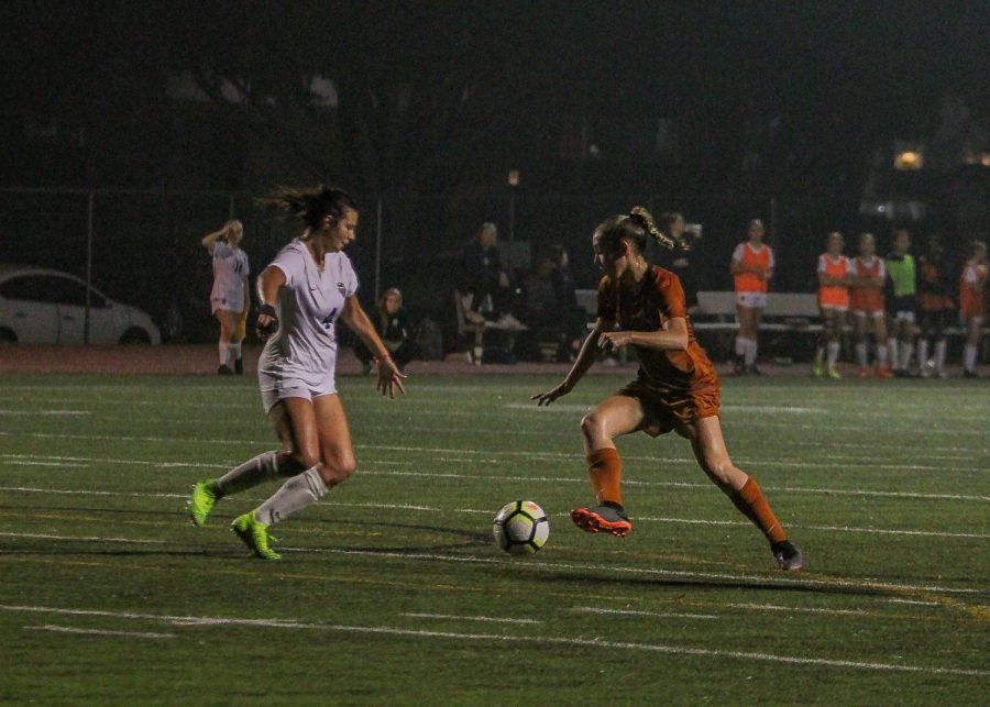 Andrea Pena 22 thwarts a Hawk as she heads towards the goal post. Pena is a forward/midfielder for the Warriors. 