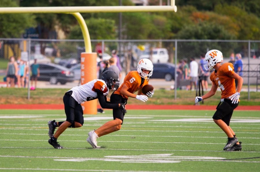 With a defensive player coming up from behind, wide receiver Lane Wood '24 attempts to slip the tight grip of a Hippo. Despite the Warriors' attempt, the Hippos would make the first touchdown of the game and maintain their lead throughout.