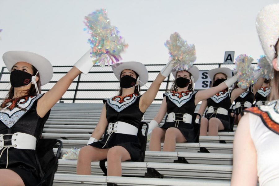 SunDancers sit in the stands, eyes on the field, preparing to perform their stand routines. The dancers pay attention to the bands signals, to know which dance to perform, as soon as the band starts.