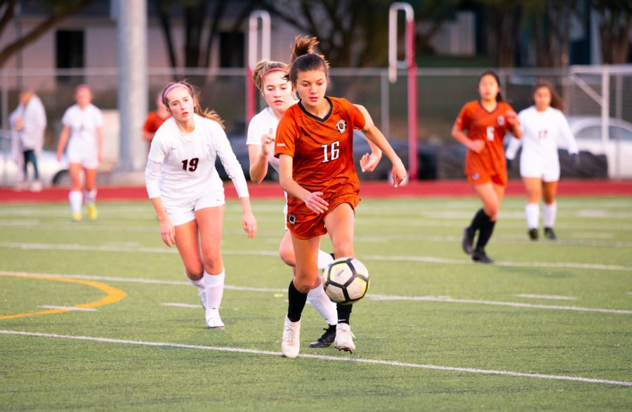 Gaining possession of the ball, forward Katie Forshay 23 dribbles the ball across the field as two opposing defenders run up from behind. Forshay was able to advance the ball downfield.