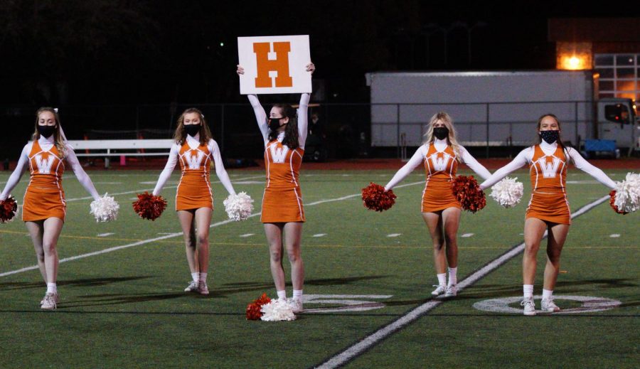 Hitting the low V in unison, Sydney Ferris 21, Ashlin Swasey 22, Claire Fleming 21, Carys Wellings 21, and Claire Pitre 21 cheer for the halftime show. The cheer team raised energy and support in the stands for the boys soccer game. 