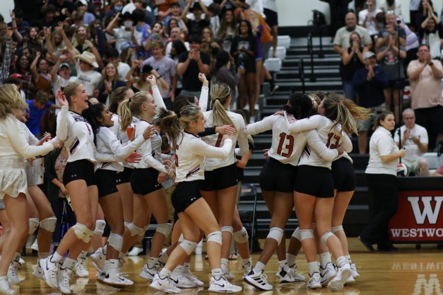 Running onto the court, the entire volleyball team celebrates their victory over the Raiders. The team won all three sets.