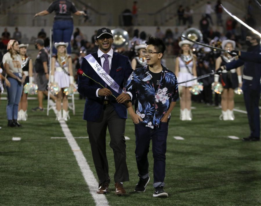 Laughing, Hrushi Saranu 22 walks down the field as he is introduced by the announcer. All of the people in the running for Homecoming king and queen walked down the field during half time.