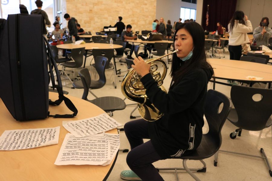 Warming up in the Cedar Ridge High School cafeteria for Region auditions, French horn player Carrie Li ‘22 plays a few measures of her etudes. 
