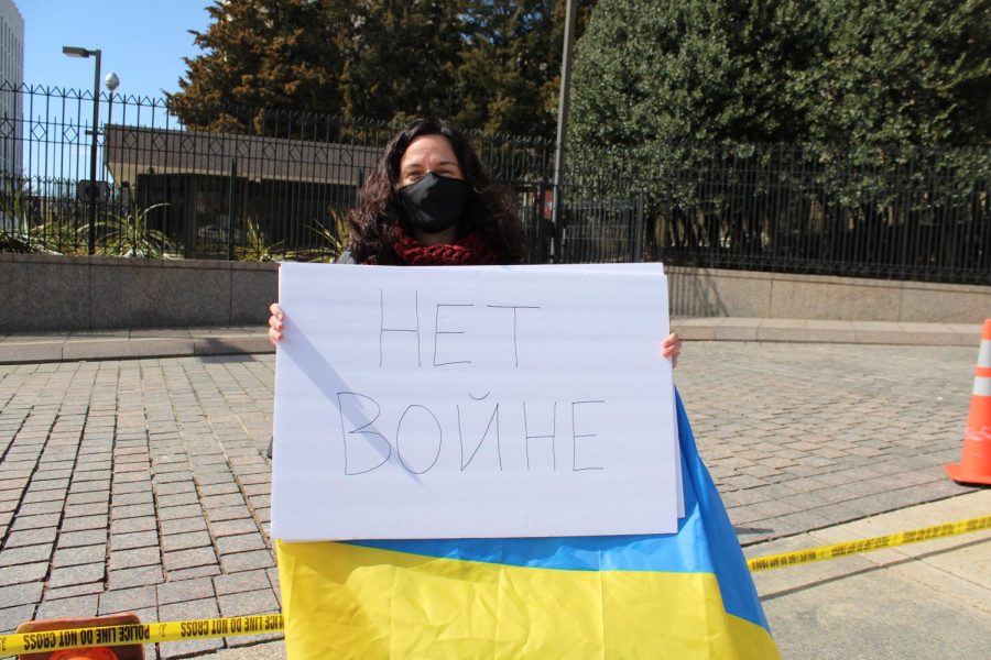 A woman holds up a sign with No War written in Russian.