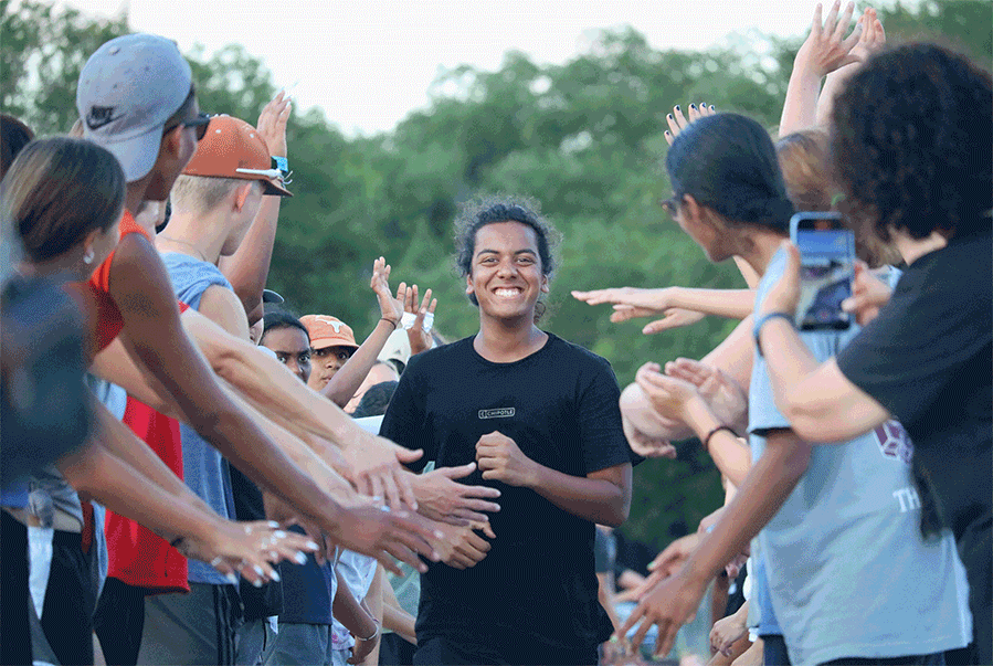 Sprinting through a tunnel of students, Rishi Baranga 23 smiles as he is cheered on by band upperclassmen. In addition to a blockhead, many members, including Baranga, were given candy and other additional treats. 
