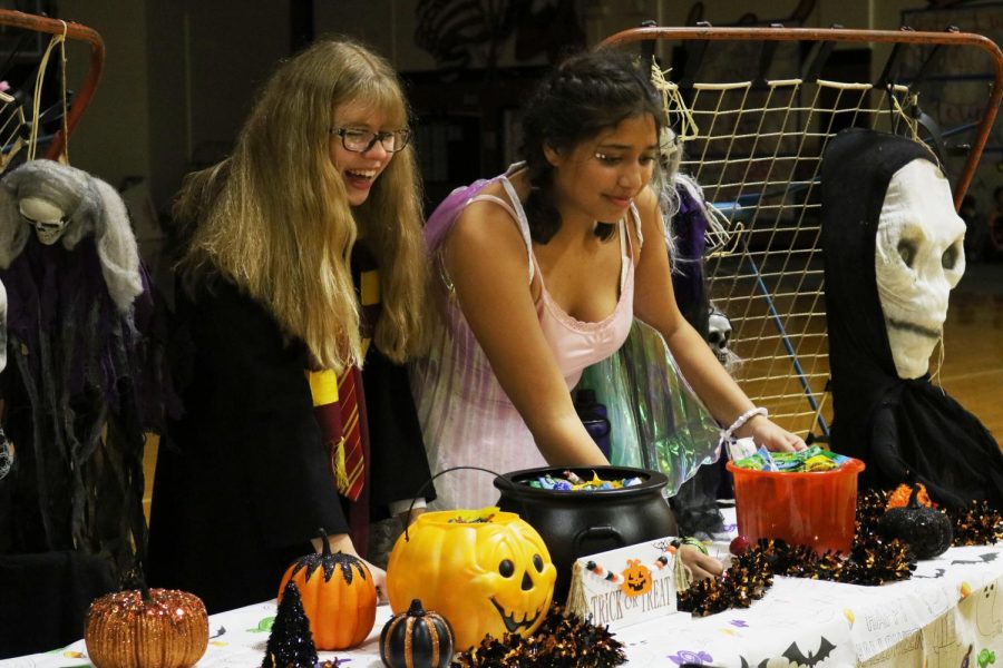 Laughing, freshmen Ella Steinheider and Hadyn Espinoza interact with trick-or-treaters. Students from each organization represented were eager to greet the attendees.  